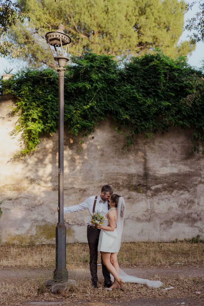 Couple kissing under a vintage lamppost in Villa Borghese during their Rome elopement.