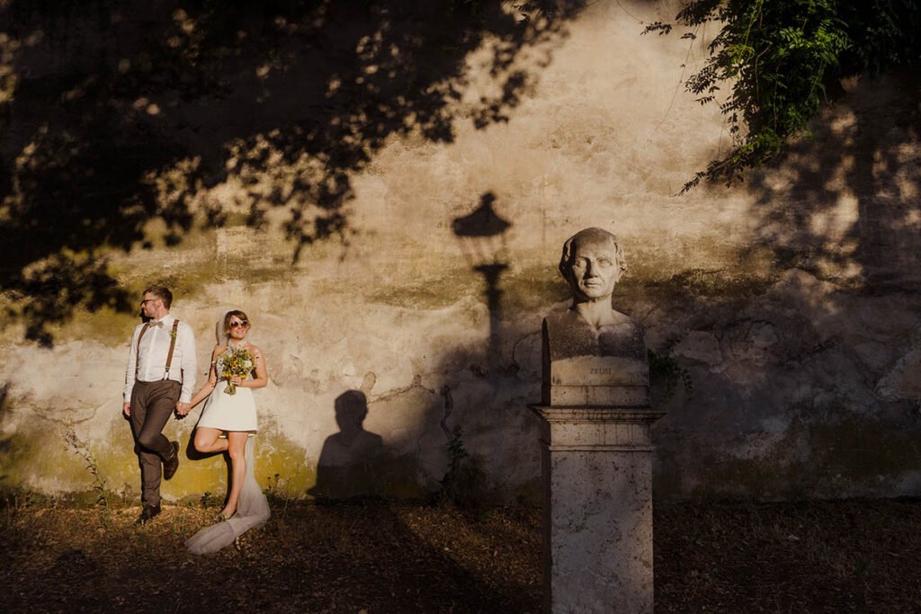 Couple standing past a Roman bust casting long shadows on the wall.