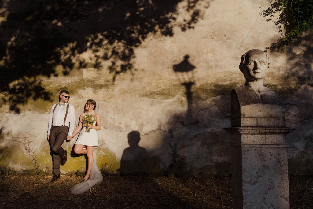 Couple standing under a lamppost with bust and long evening shadows behind.