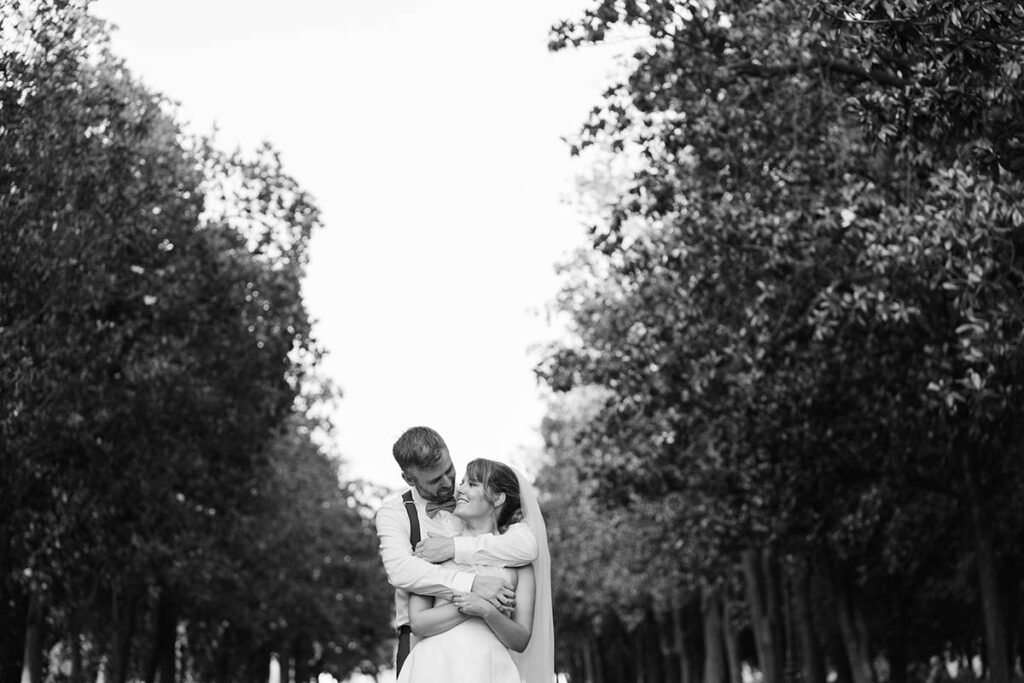Black and white photo of couple embracing in a wooded park during their elopement.