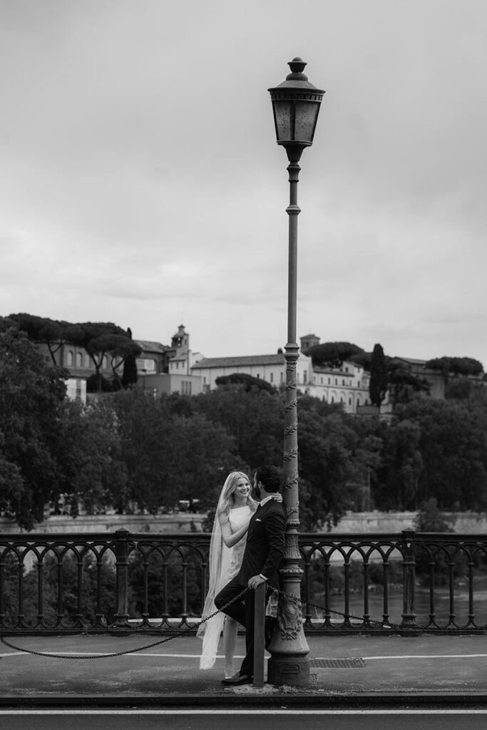 Bride smiling at groom on a Roman bridge at golden hour – candid moment by a local elopement photographer in Rome