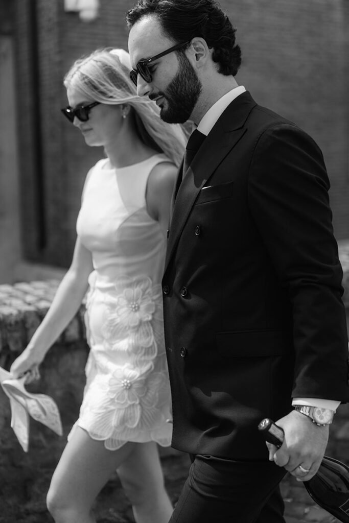 Close-up of bride and groom walking with a bottle of prosecco – elegant editorial elopement in Rome