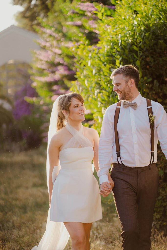 Bride and groom walking through an open field with blooming tree