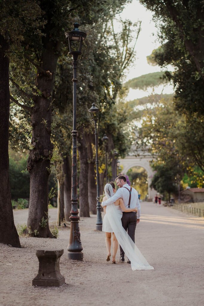 Couple sharing an intimate moment among the trees of Villa Borghese.