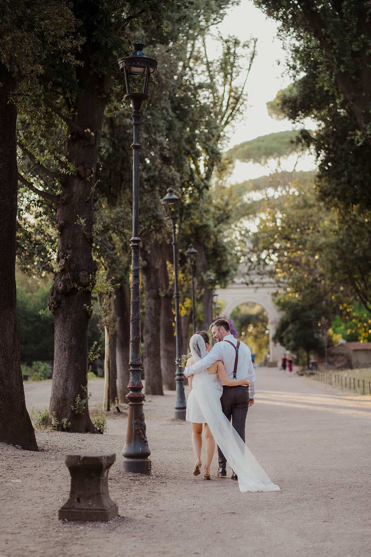 Couple sharing an intimate moment among the trees of Villa Borghese.
