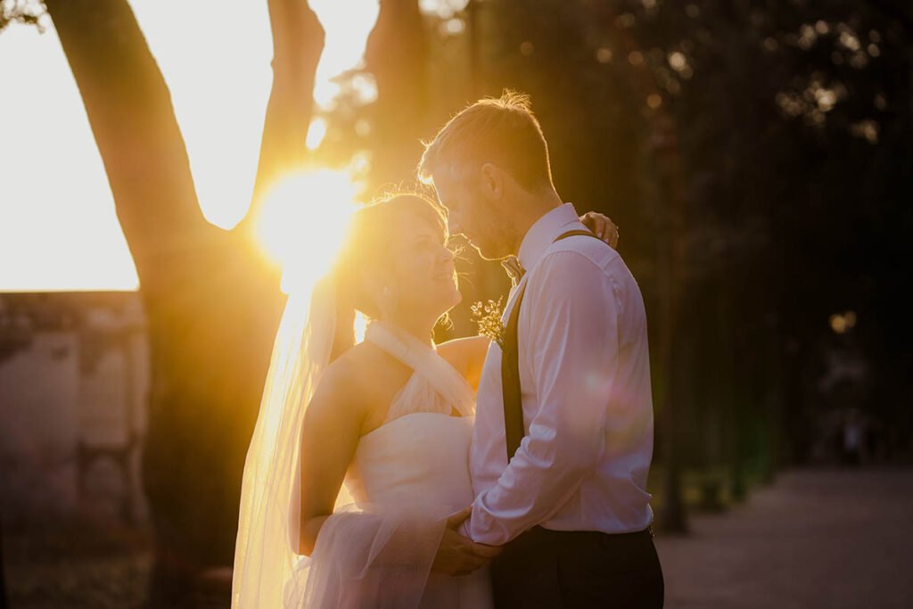 Couple sharing a kiss in soft light on a path through Villa Borghese.
