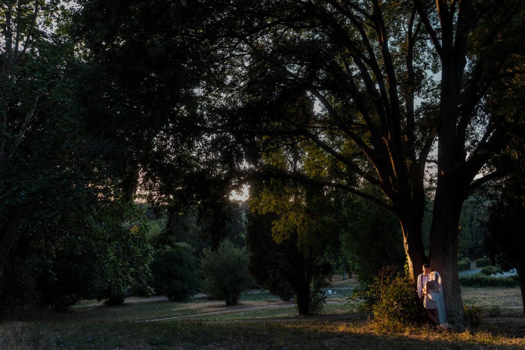 Shaded tree-lined path in Villa Borghese during golden hour.