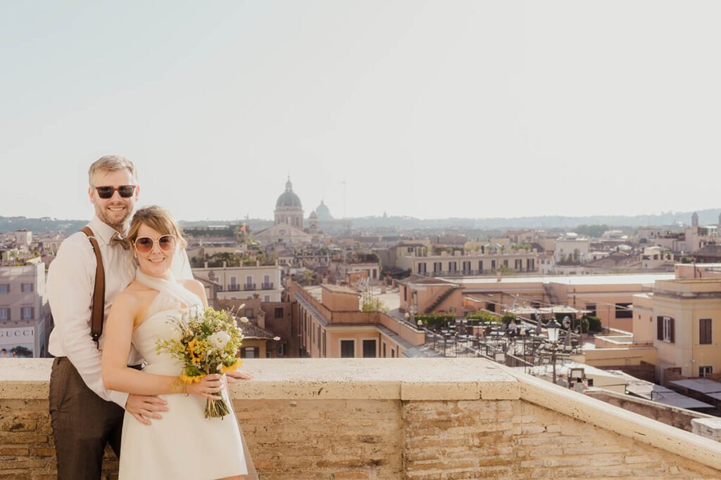 Bride smiling at the camera while holding her bouquet in the sunlight.