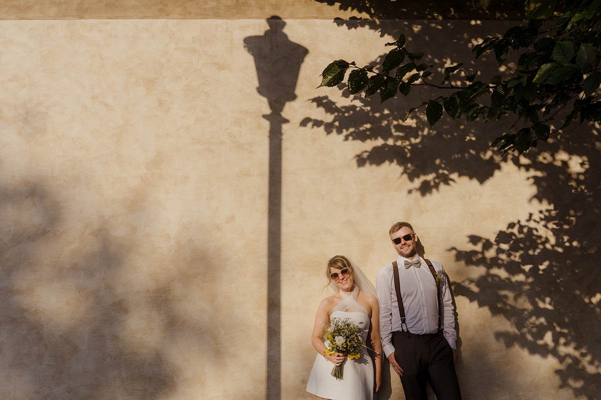 Couple standing under a vintage lamppost casting a long shadow.