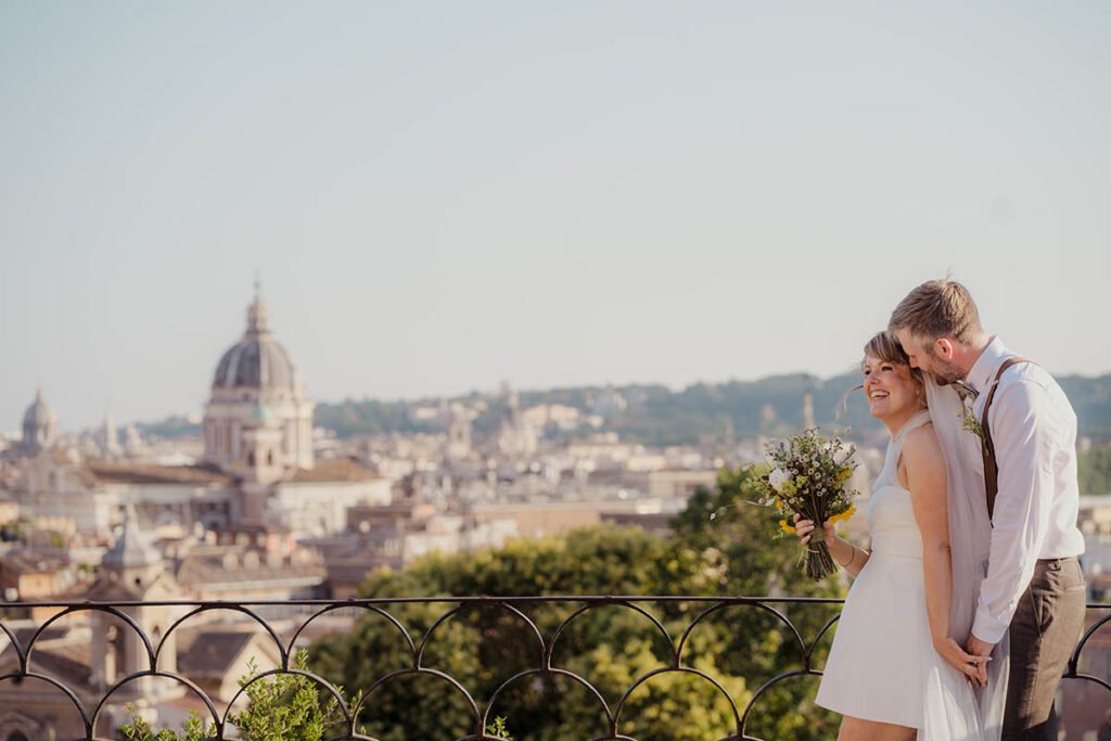 Bride smiling while leaning back in the groom’s arms in soft sunlight