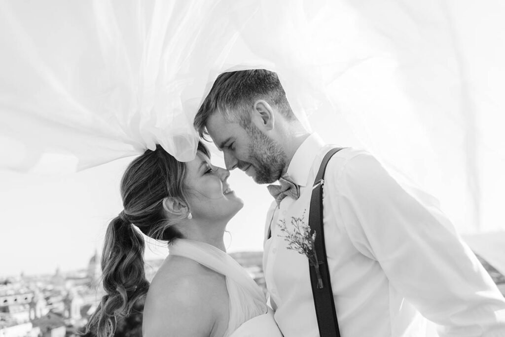 Couple looking into each other’s eyes as the bride’s veil flows in the air.