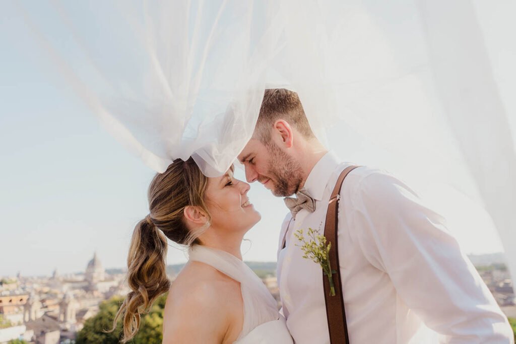 Bride smiling with veil flying in the air next to the groom.