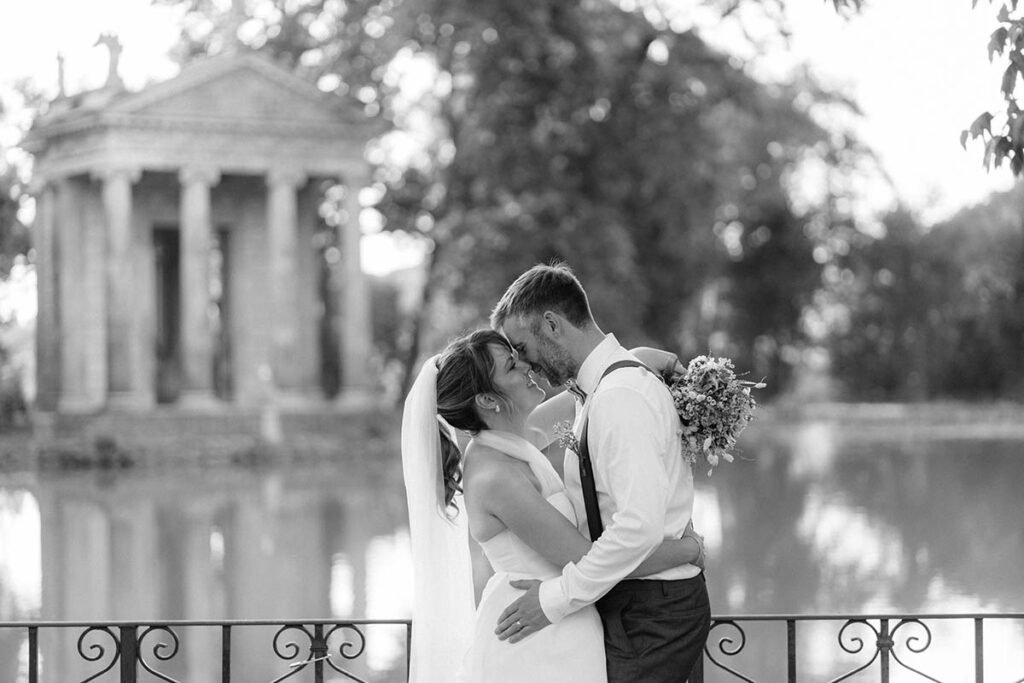 Groom embracing the bride in front of the Temple of Asclepius in black and white.