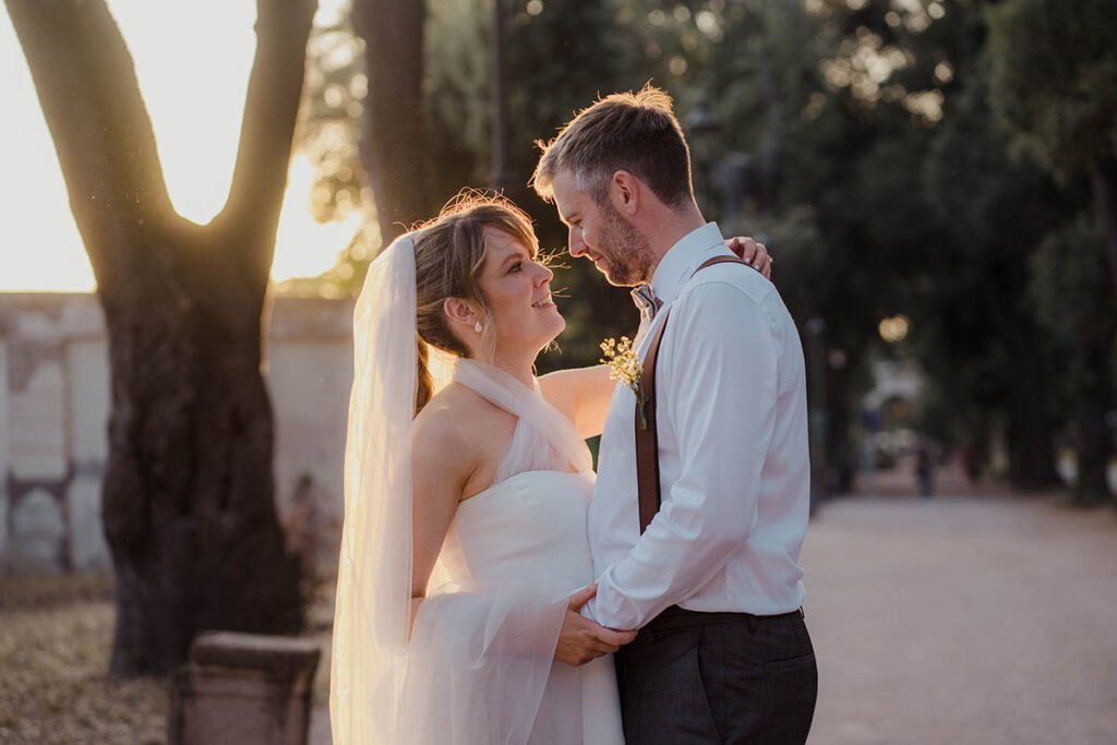 Groom holding the bride’s waist while gazing into her eyes at sunset in Rome.