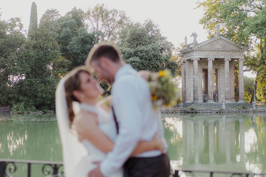 Groom kissing the bride's forehead near temples of esculapio in Villa Borghese.