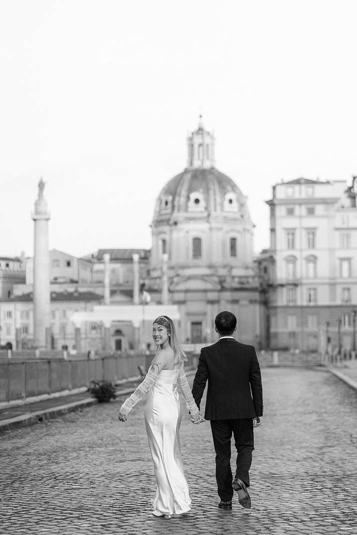 Bride and groom walking hand in hand near Imperial Forum in Rome