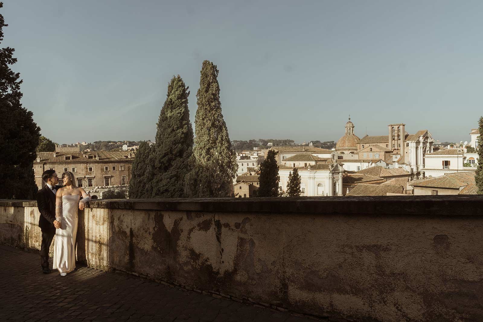Bride and groom leaning on railing with Roman Forum view