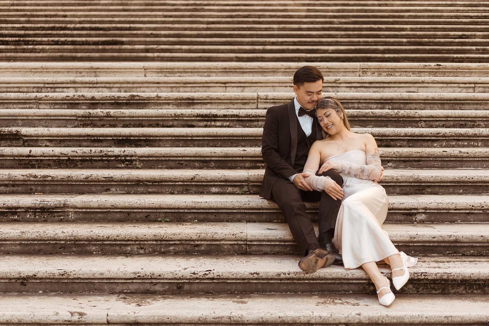 Bride leaning on groom while sitting on historic Rome stairs during elopement