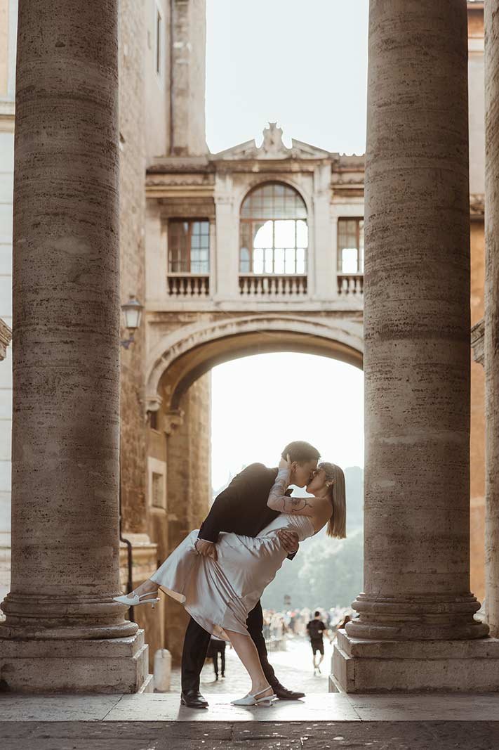 Rome elopement couple embracing under monumental stone arch