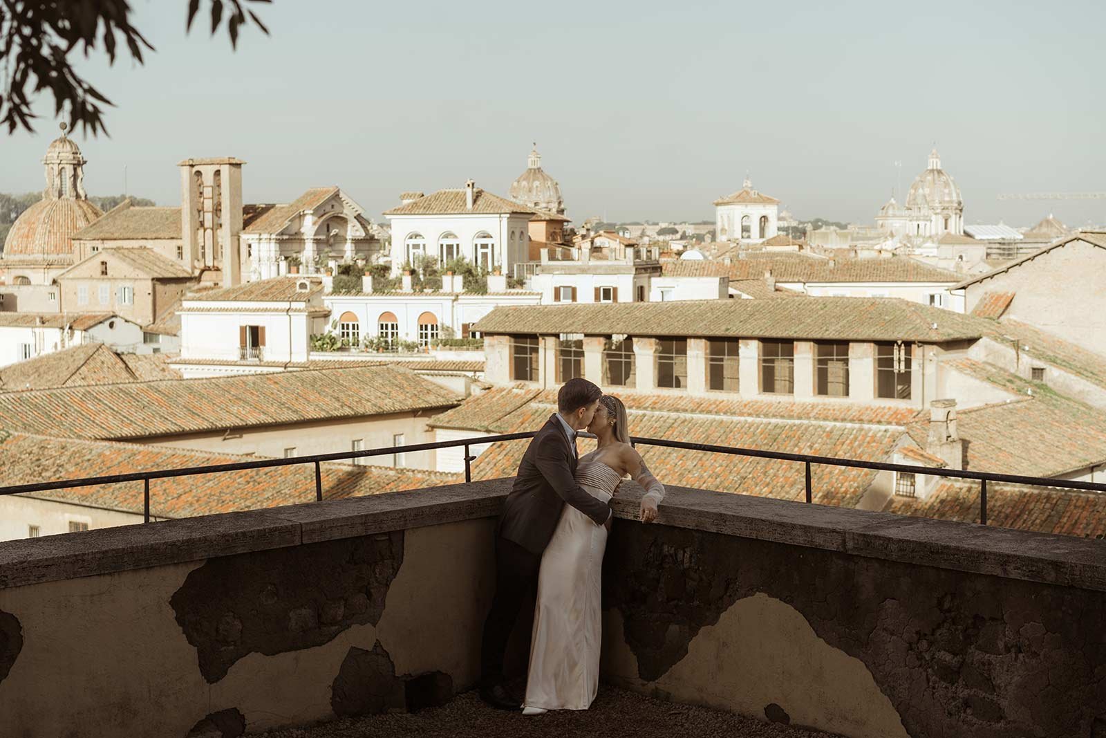 Couple kissing on terrace with panoramic view of Rome during elopement