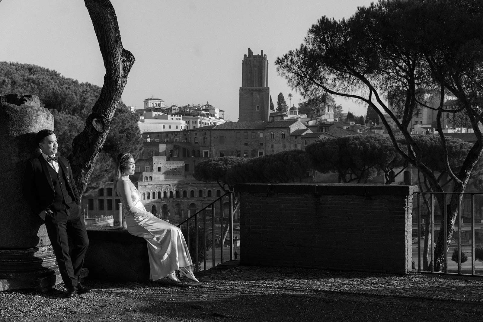 Bride sitting on stone wall overlooking Rome skyline during elopement