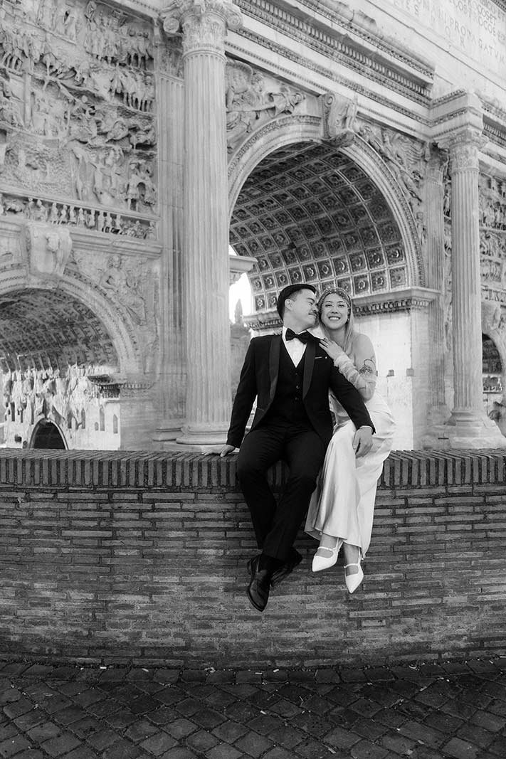 Couple sitting together under Arch of Constantine during Rome elopement