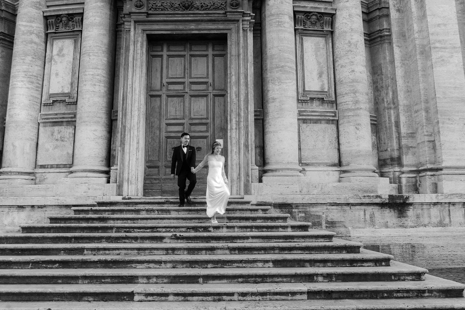 Bride leading groom down historic church steps during Rome elopement