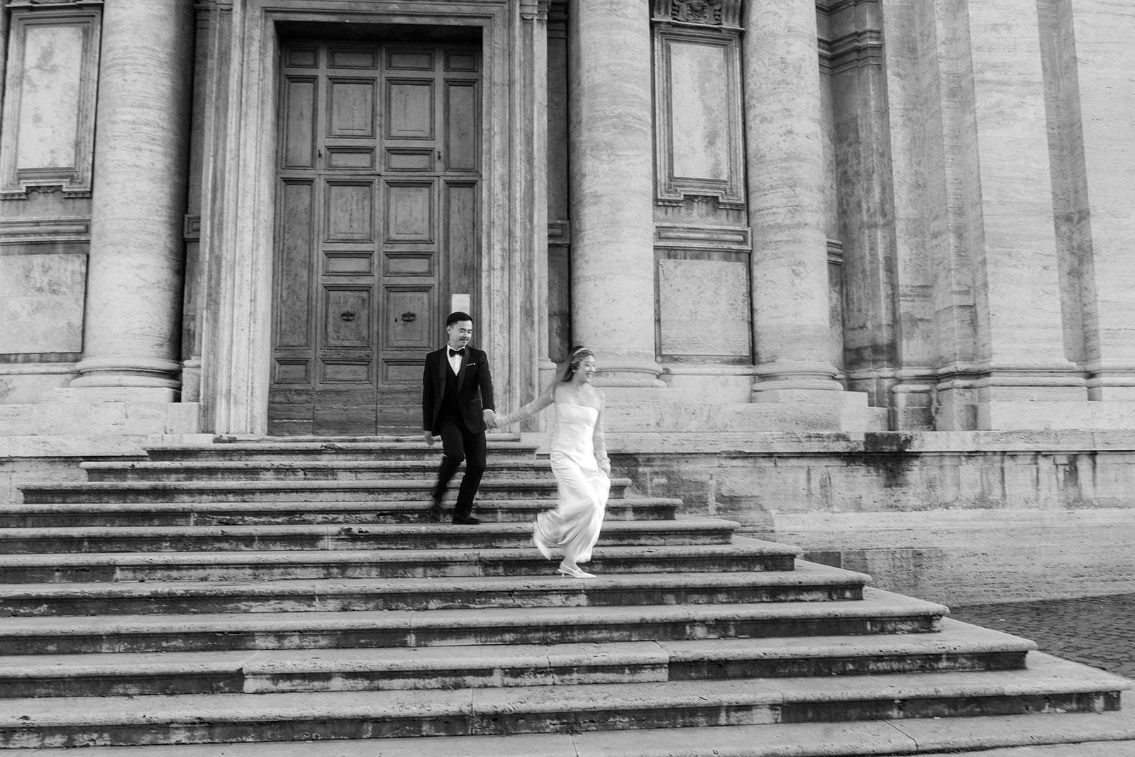 Black and white Rome elopement couple walking down monumental church stairs