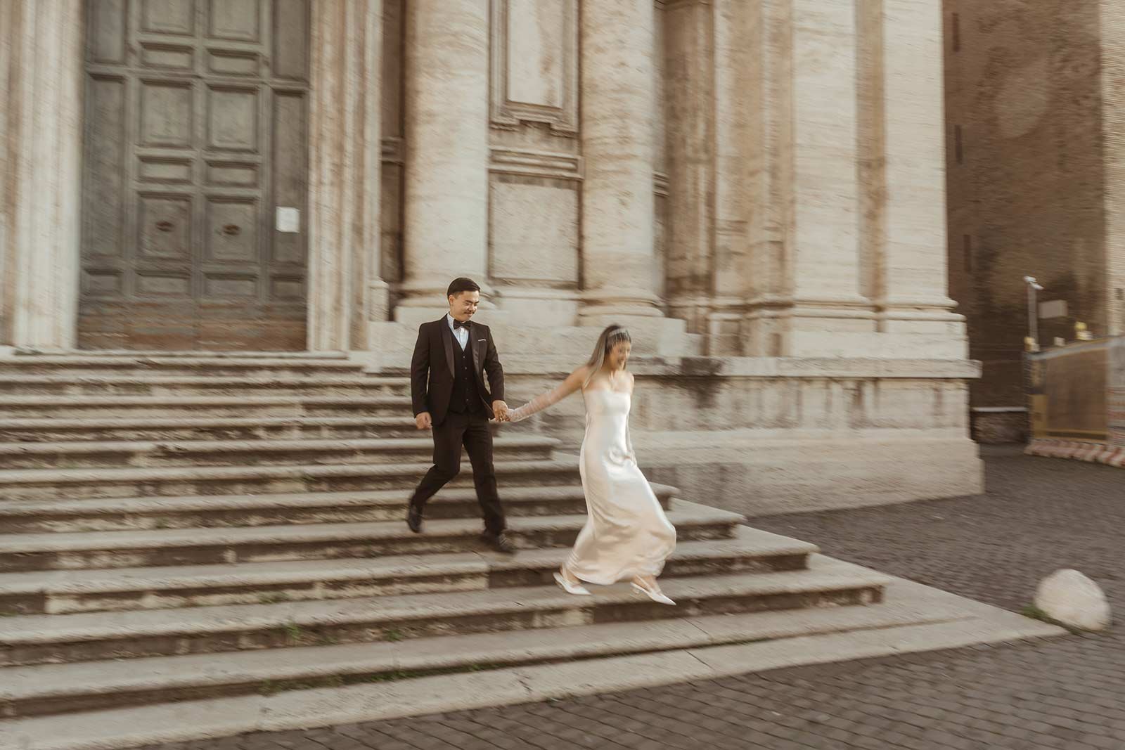 Couple descending the grand stairs of a Roman basilica during elopement photoshoot