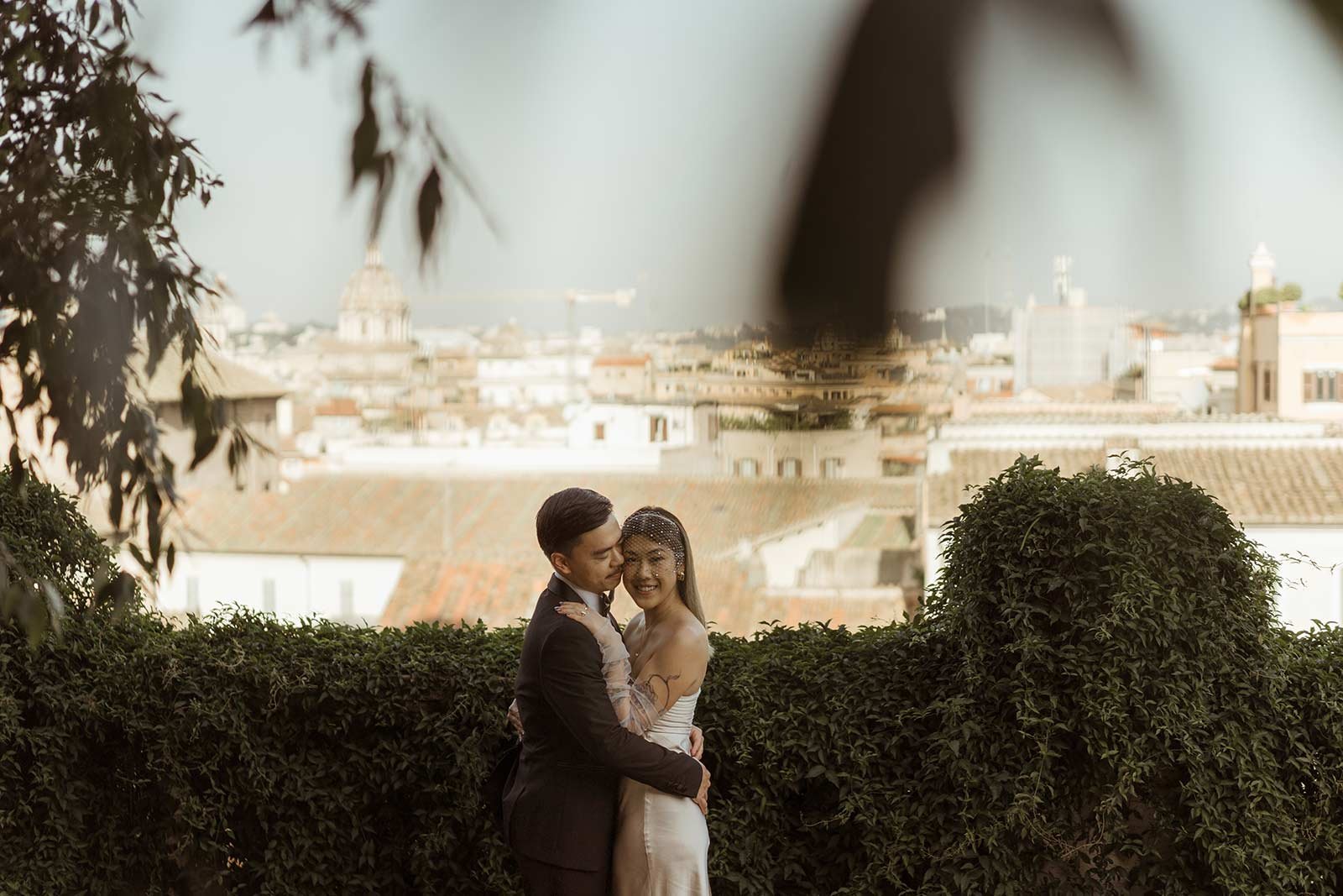 Bride and groom standing together in a Roman garden during their elopement