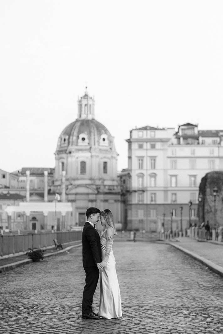 Rome elopement couple standing hand in hand with a historic dome in the background