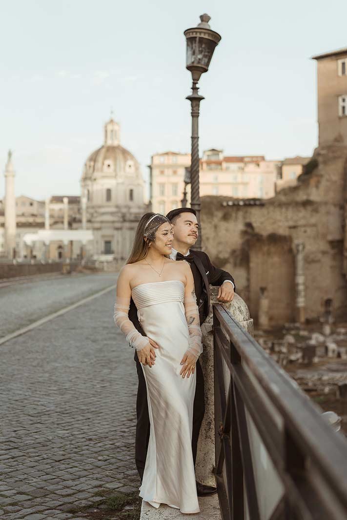 Bride and groom leaning on a railing overlooking the Roman Forum during their elopement