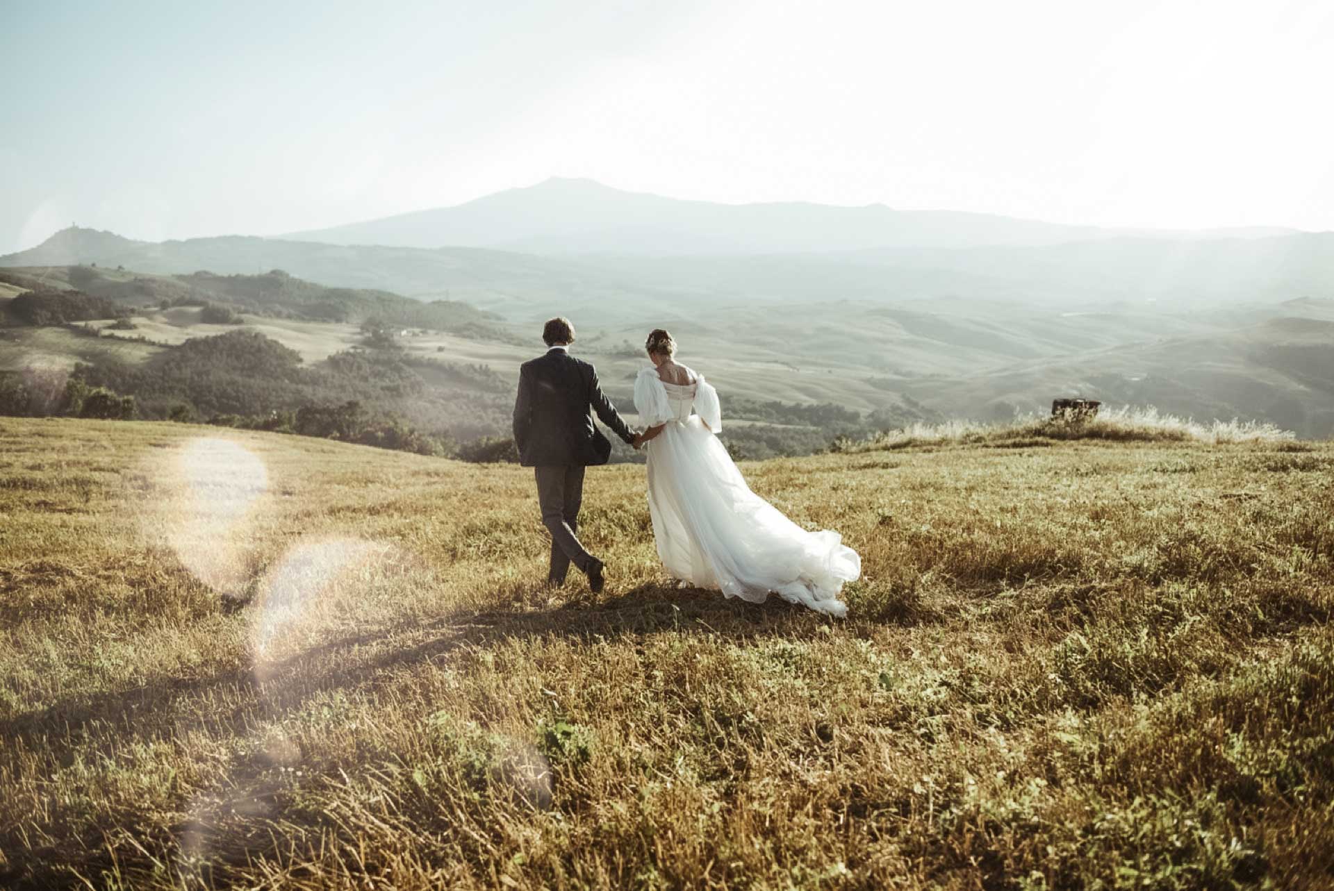 Couple walking through the rolling hills of Tuscany during an intimate elopement in Italy.