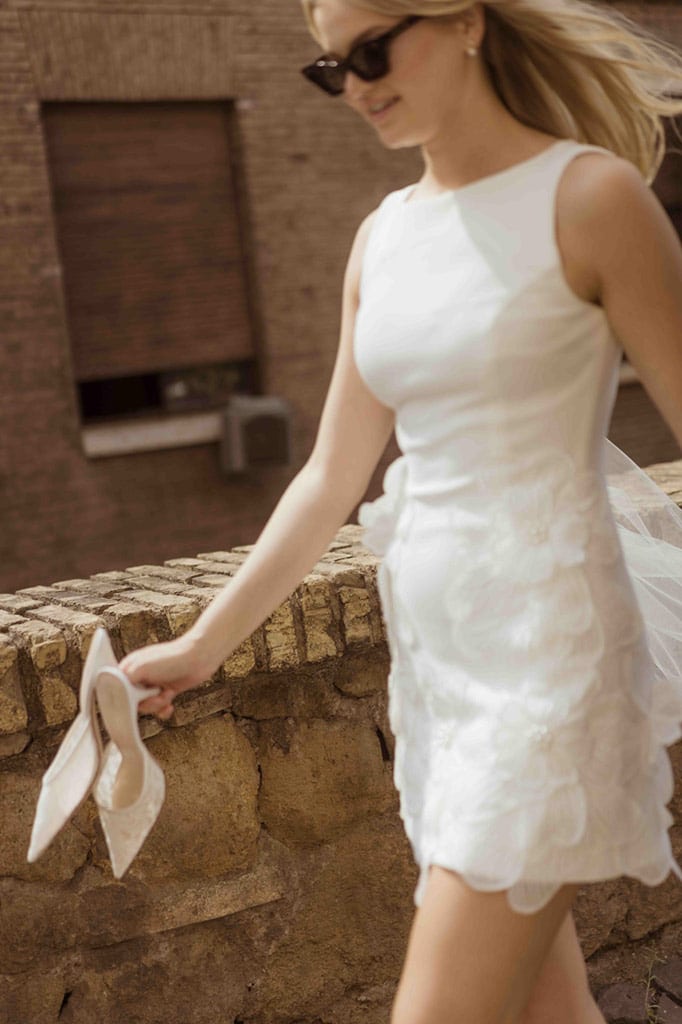 Bride taking off her heels while walking on cobblestones in Italy